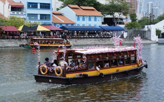 Serene cruise ship gliding through Singapore River, offering passengers a delightful journey with captivating scenic views and joyful moments.